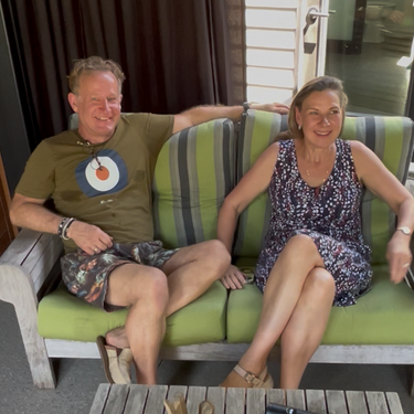 Two people are sitting on a green couch with a table in front of them